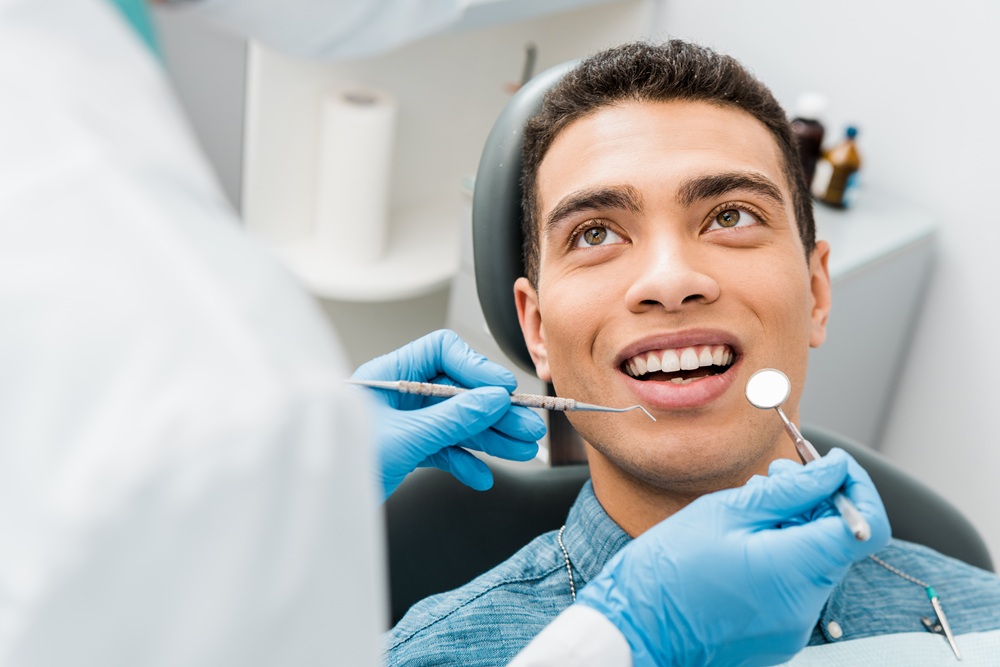 Patient smiling during a cosmetic dental procedure to smooth and contour teeth for a balanced appearance – tooth recontouring